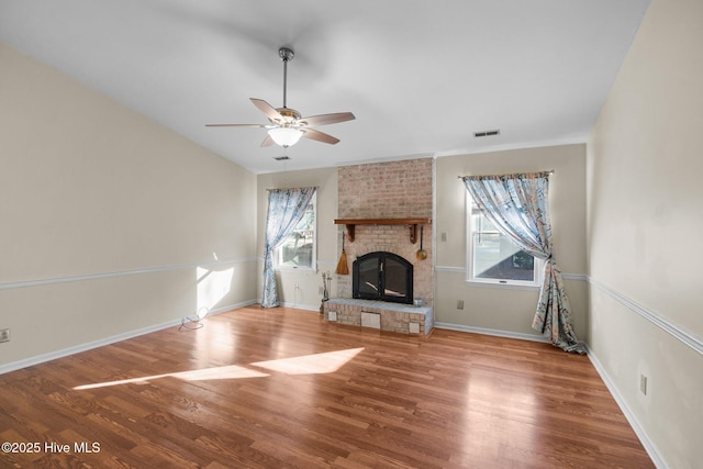 unfurnished living room featuring a wealth of natural light, visible vents, wood finished floors, and ceiling fan