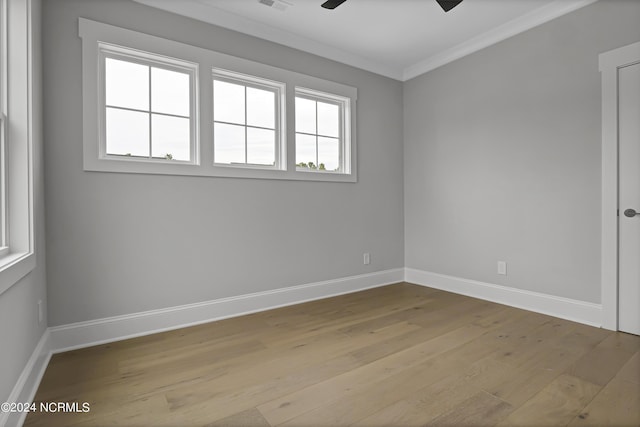 spare room with wood finished floors, a ceiling fan, baseboards, visible vents, and crown molding