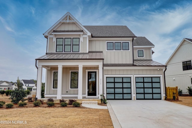 modern farmhouse style home featuring a standing seam roof, covered porch, board and batten siding, an attached garage, and metal roof