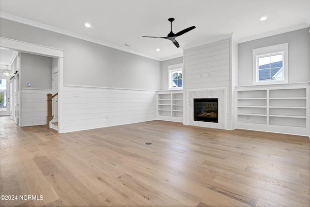 unfurnished living room with light wood-type flooring, a wainscoted wall, and a high end fireplace