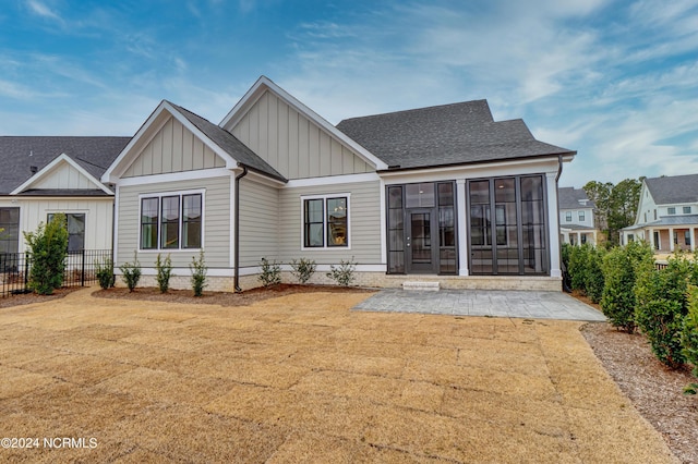 rear view of property featuring a lawn, a patio, fence, roof with shingles, and board and batten siding