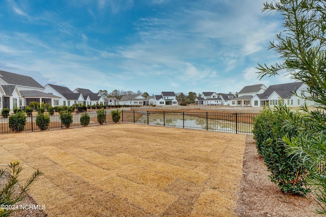 view of yard with a residential view, a water view, and fence