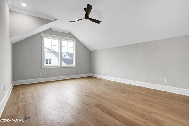 additional living space with hardwood / wood-style flooring, a ceiling fan, baseboards, and vaulted ceiling