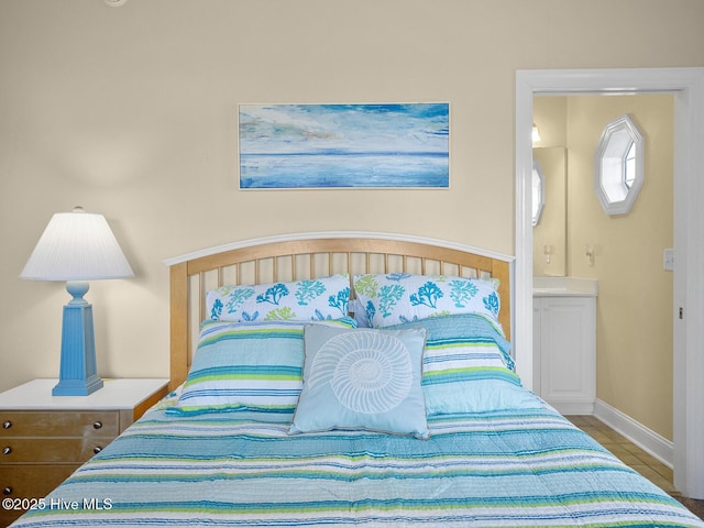 tiled bedroom featuring baseboards and ensuite bathroom