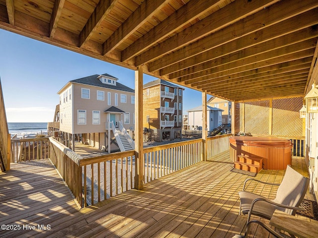 wooden deck featuring a water view and a hot tub