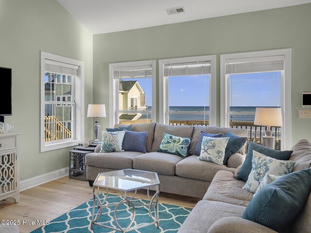 living room featuring light wood-type flooring, visible vents, and baseboards