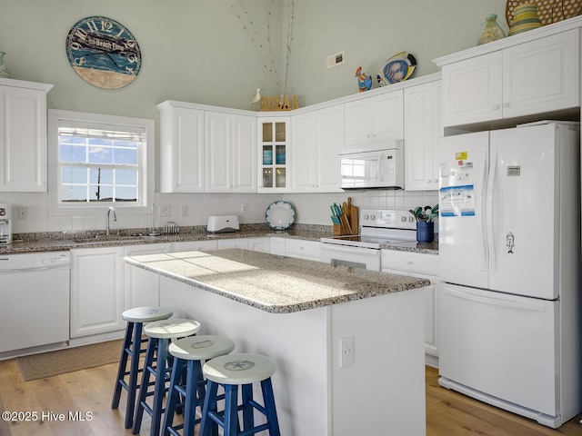 kitchen with decorative backsplash, white appliances, light wood-type flooring, and a sink