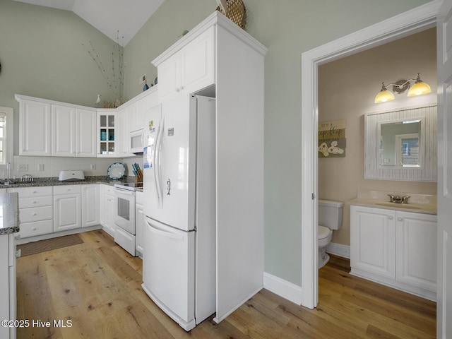 kitchen featuring white appliances, white cabinets, light wood-style floors, and a sink