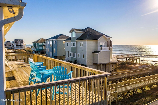 deck featuring a view of the beach, a water view, and a residential view