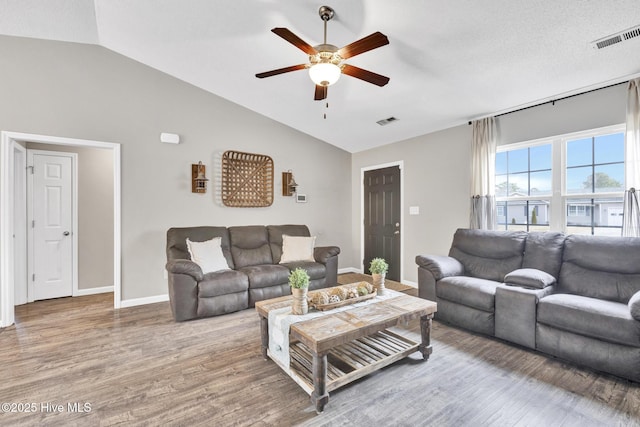 living area with visible vents, baseboards, lofted ceiling, wood finished floors, and a ceiling fan