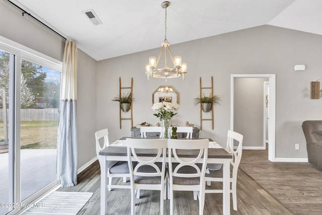 dining space with lofted ceiling, wood finished floors, visible vents, and a chandelier