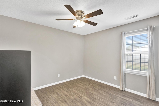 unfurnished room with visible vents, baseboards, wood finished floors, a textured ceiling, and a ceiling fan