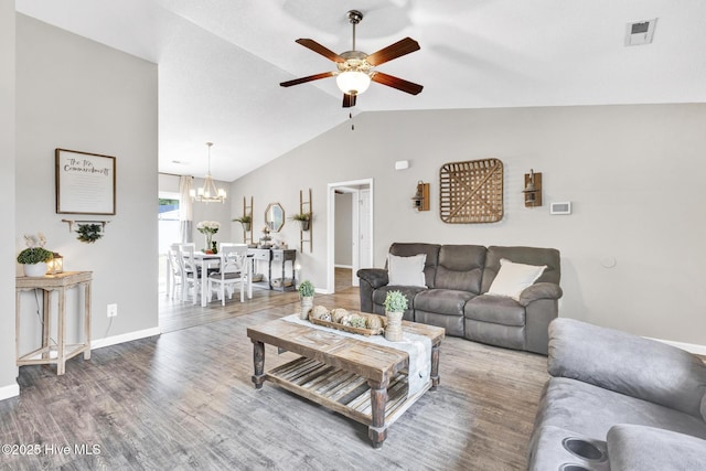 living room with visible vents, ceiling fan with notable chandelier, wood finished floors, baseboards, and vaulted ceiling