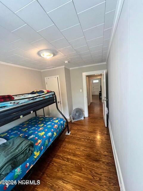 bedroom with crown molding, wood finished floors, and baseboards