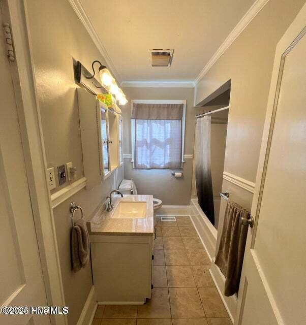 full bathroom featuring tile patterned flooring, visible vents, toilet, shower / tub combo with curtain, and ornamental molding