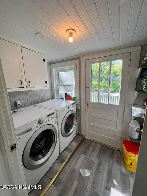 clothes washing area with washer and dryer, wood finished floors, cabinet space, and wooden ceiling