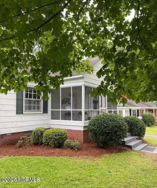 view of side of property with a yard, a sunroom, and crawl space