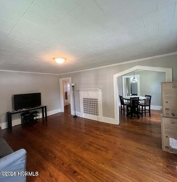 living room with crown molding, wood finished floors, and baseboards