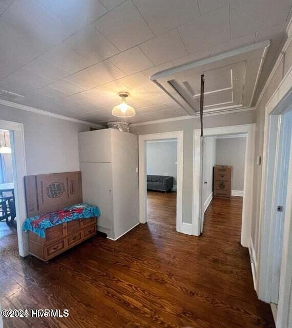 hall with ornamental molding, baseboards, and wood finished floors