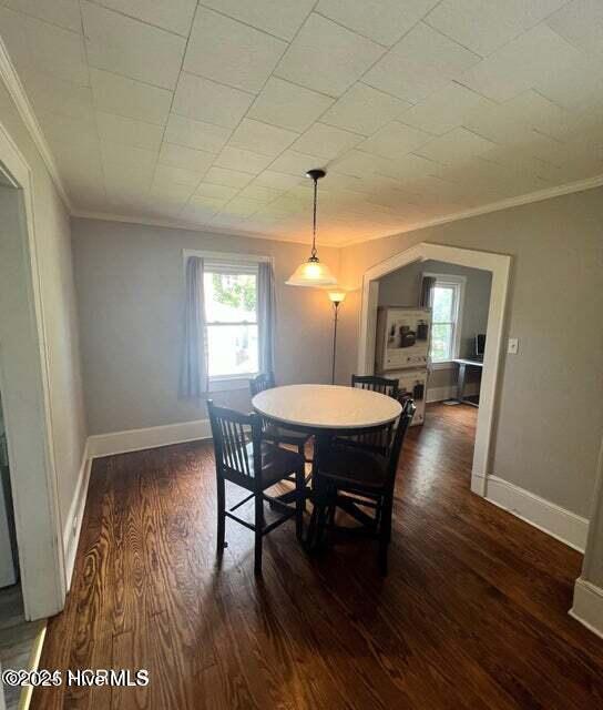 dining space featuring baseboards, wood finished floors, and ornamental molding