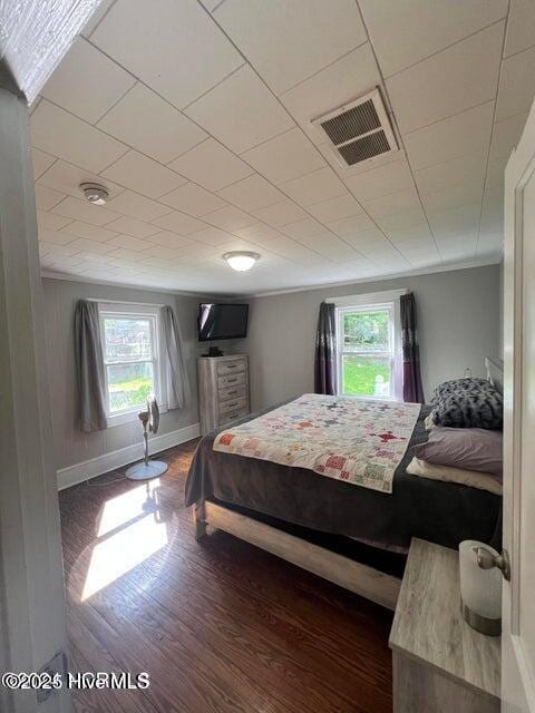 bedroom featuring multiple windows, wood finished floors, visible vents, and ornamental molding