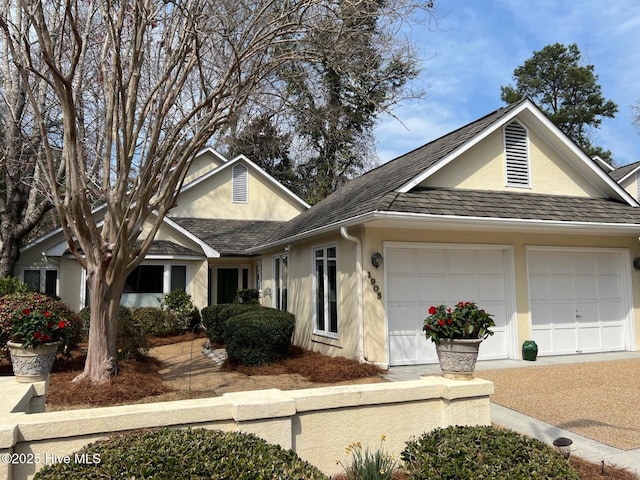 ranch-style house featuring stucco siding, an attached garage, and a shingled roof