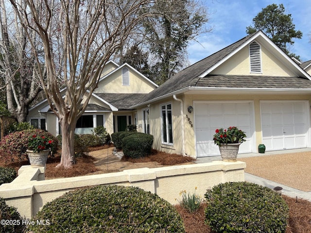 view of front of house with a garage, roof with shingles, and stucco siding