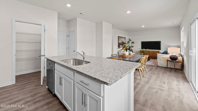 kitchen featuring recessed lighting, stainless steel dishwasher, light wood-type flooring, and a sink