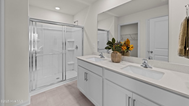 bathroom featuring a sink, a spacious closet, double vanity, and a shower stall