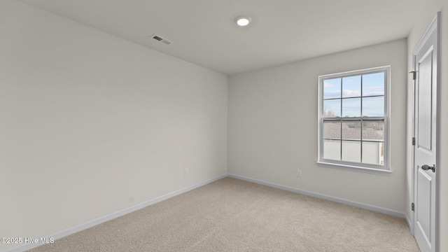 unfurnished room with light carpet, visible vents, and baseboards