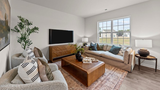 living room with visible vents, baseboards, and light wood finished floors