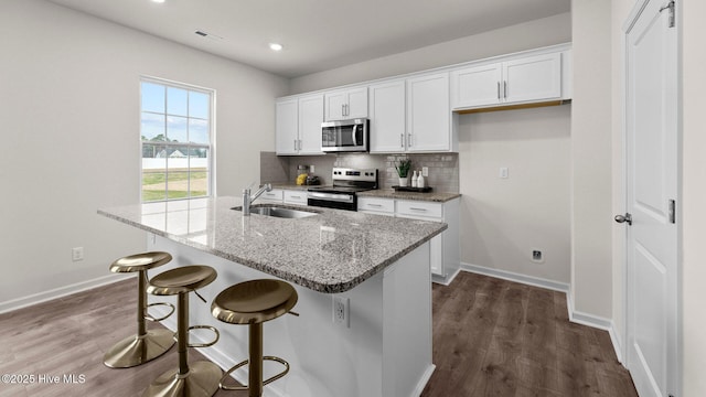 kitchen featuring visible vents, a sink, white cabinetry, appliances with stainless steel finishes, and decorative backsplash