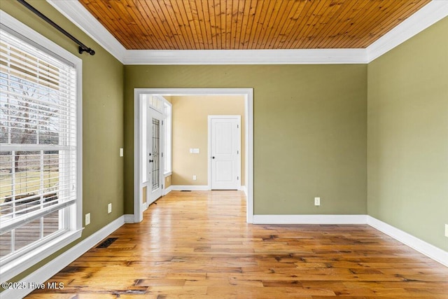 spare room with crown molding, plenty of natural light, baseboards, and light wood finished floors