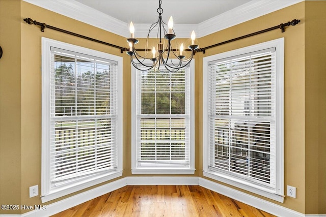 unfurnished dining area with a chandelier, crown molding, and wood finished floors