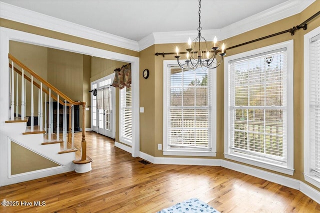 entryway with an inviting chandelier, crown molding, wood finished floors, and a healthy amount of sunlight