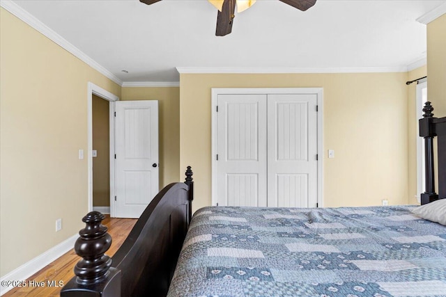 bedroom with a closet, ornamental molding, baseboards, and wood finished floors