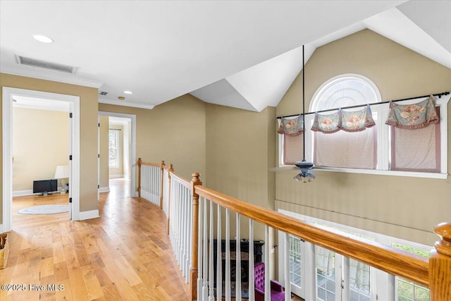 corridor with wood finished floors, baseboards, visible vents, vaulted ceiling, and an upstairs landing