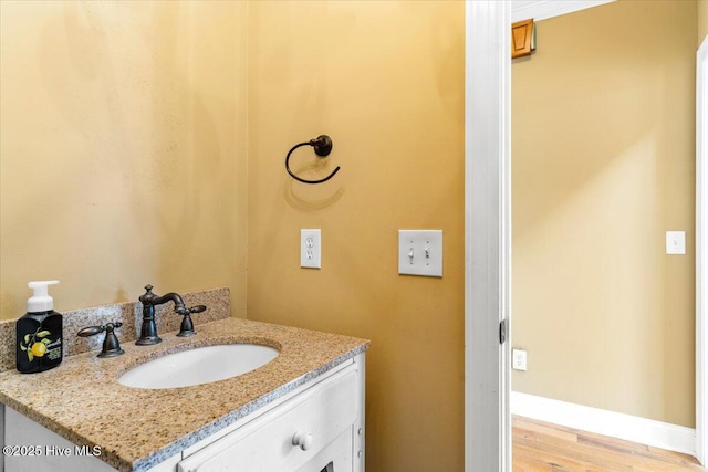 bathroom featuring baseboards, wood finished floors, and vanity