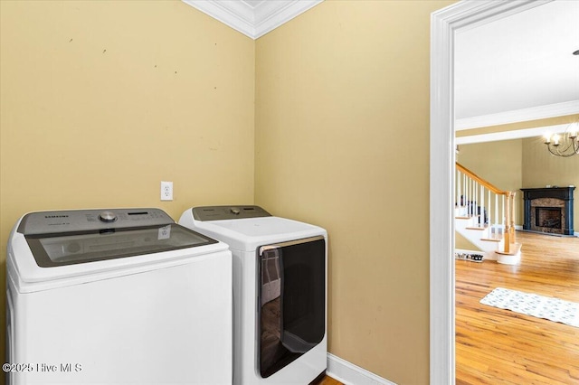 washroom with wood finished floors, an inviting chandelier, laundry area, separate washer and dryer, and ornamental molding