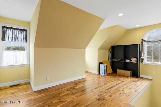 bonus room with a wealth of natural light, visible vents, lofted ceiling, and wood finished floors