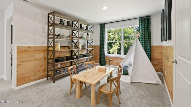 dining area featuring a wainscoted wall, visible vents, wood walls, and carpet flooring