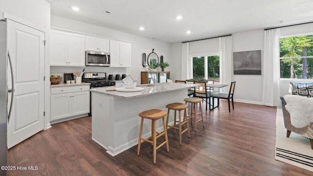 kitchen with recessed lighting, stainless steel microwave, dark wood-style flooring, and white cabinetry