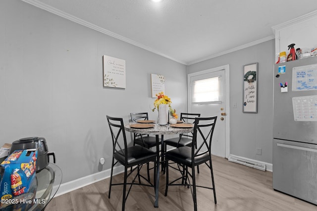 dining area featuring baseboards, wood finished floors, and crown molding