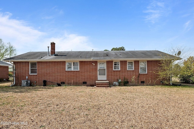 back of house with crawl space, entry steps, a chimney, and brick siding