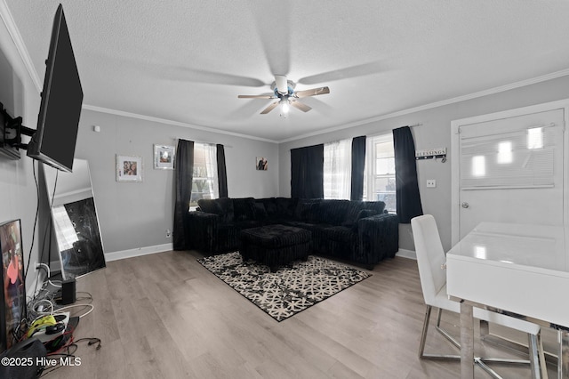 living area with crown molding, a ceiling fan, and a wealth of natural light