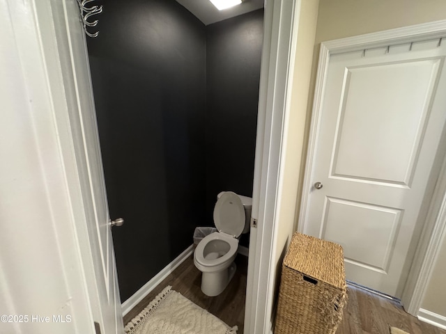 bathroom with toilet, baseboards, and wood finished floors