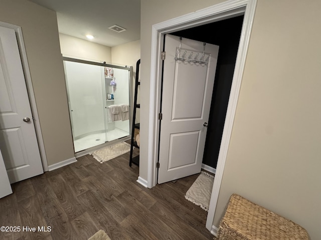 bathroom featuring visible vents, a stall shower, baseboards, and wood finished floors