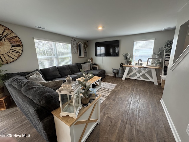 living area featuring dark wood finished floors, visible vents, a healthy amount of sunlight, and baseboards