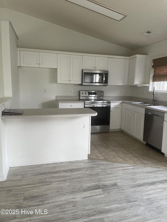 7223 Konlack Ct, Wilmington, NC 28411 - kitchen featuring white cabinets, appliances with stainless steel finishes, a sink, and lofted ceiling