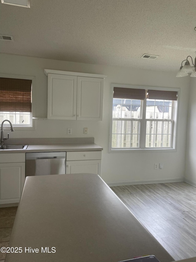 7223 Konlack Ct, Wilmington, NC 28411 - kitchen with a textured ceiling, white cabinets, visible vents, dishwasher, and a sink